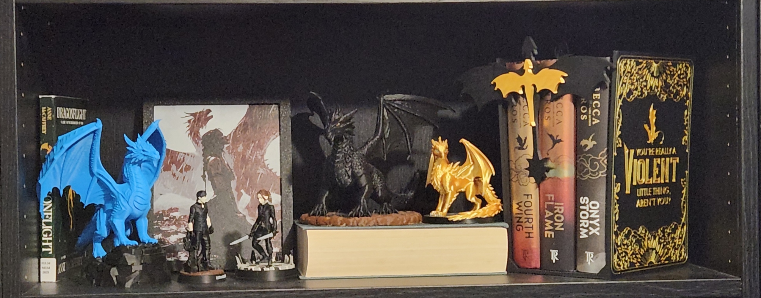 Blue, black, and gold 3D-printed dragons displayed beside my Empyrean books on a black bookshelf