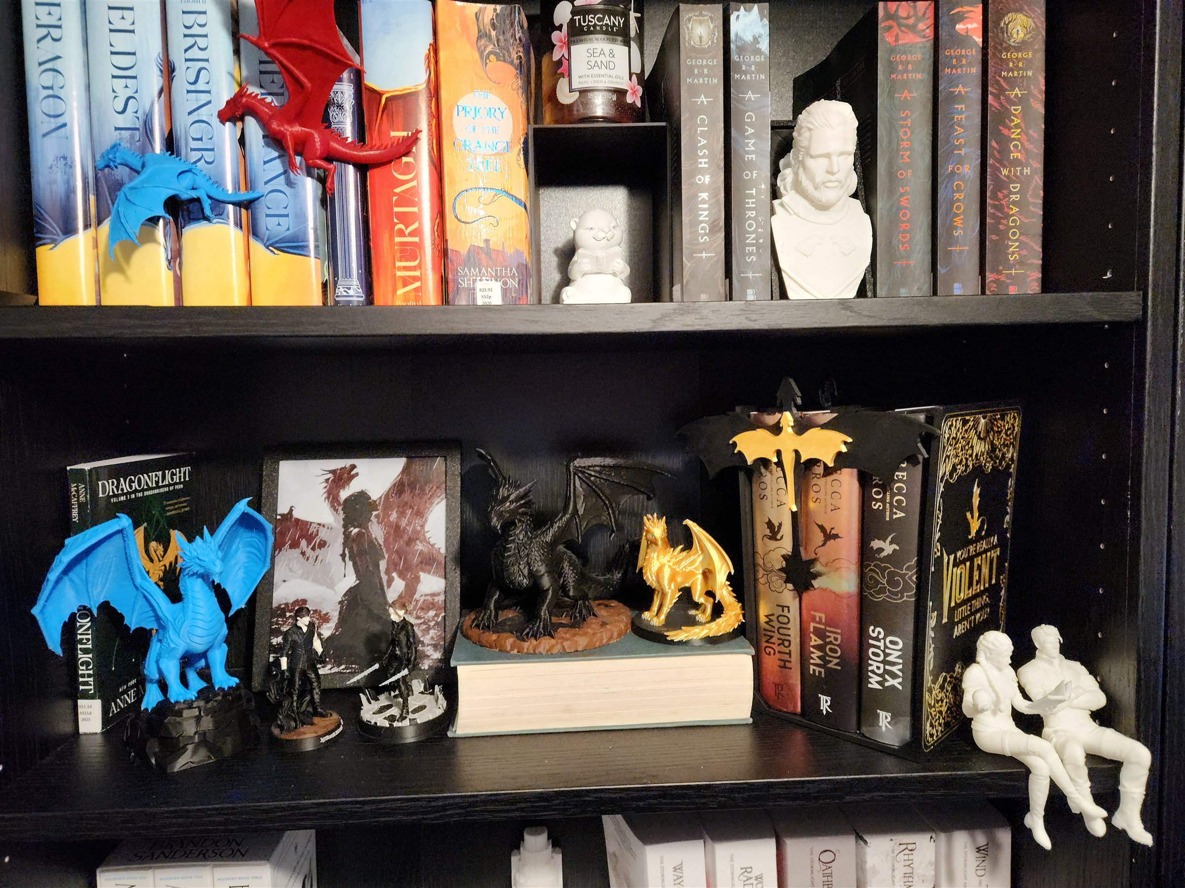 My fantasy bookshelf displaying novels, colorful 3D-printed dragons, character figures, a bust, and my Empyrean Wing and Claw editions