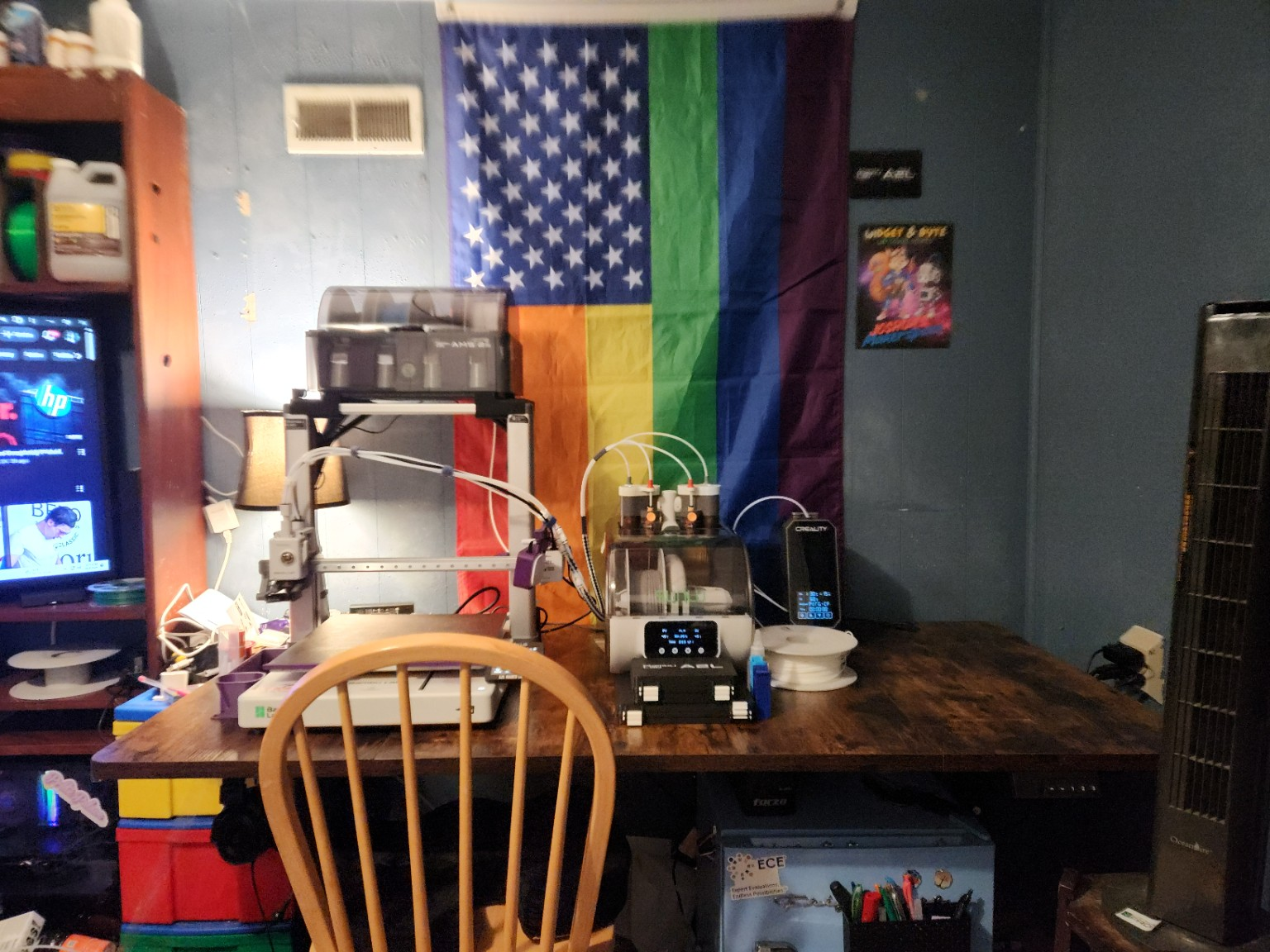 My working 3D-printing station with a large Bambu Lab printer, a top-mounted four-spool filament system, an AMS Lite heater setup, and a standalone filament dryer on the workbench.