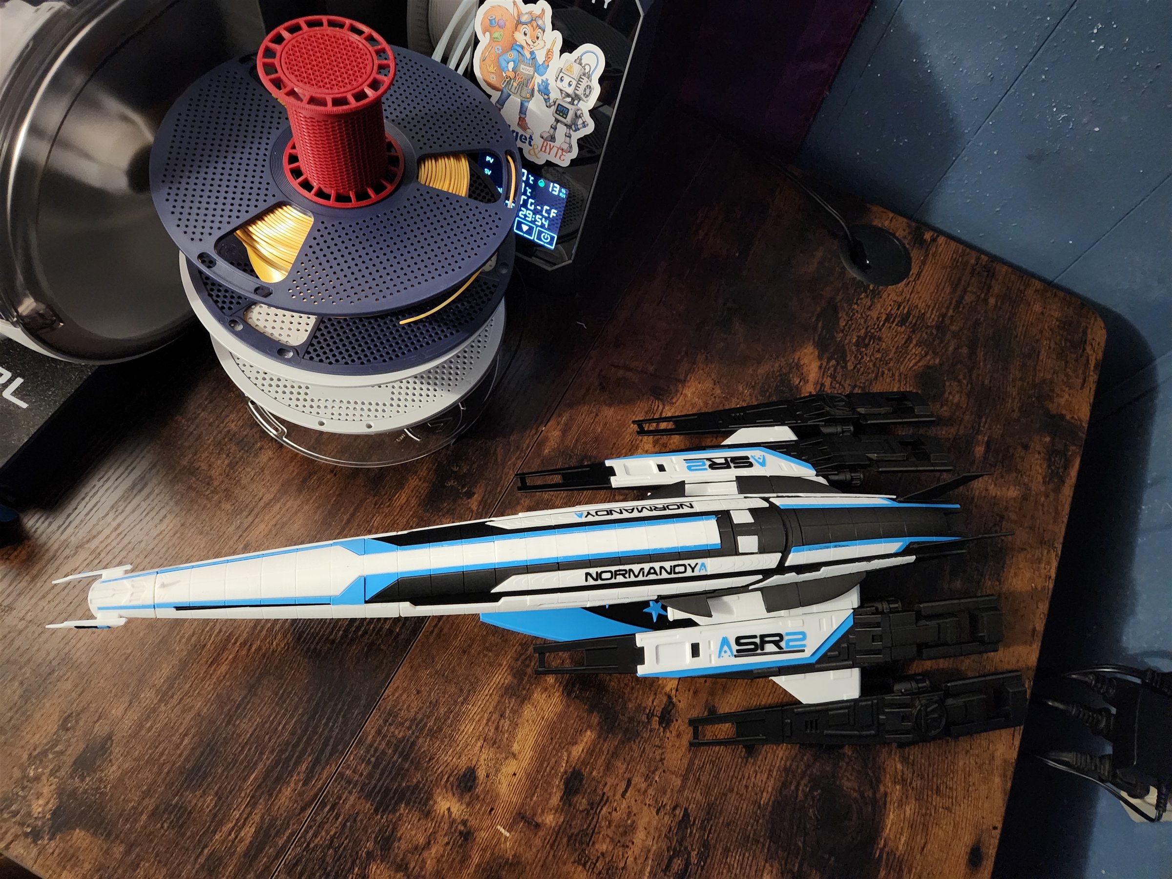 My black, white, and blue Normandy SR-2 model resting on the Makerspace worktable beside stacked filament spools