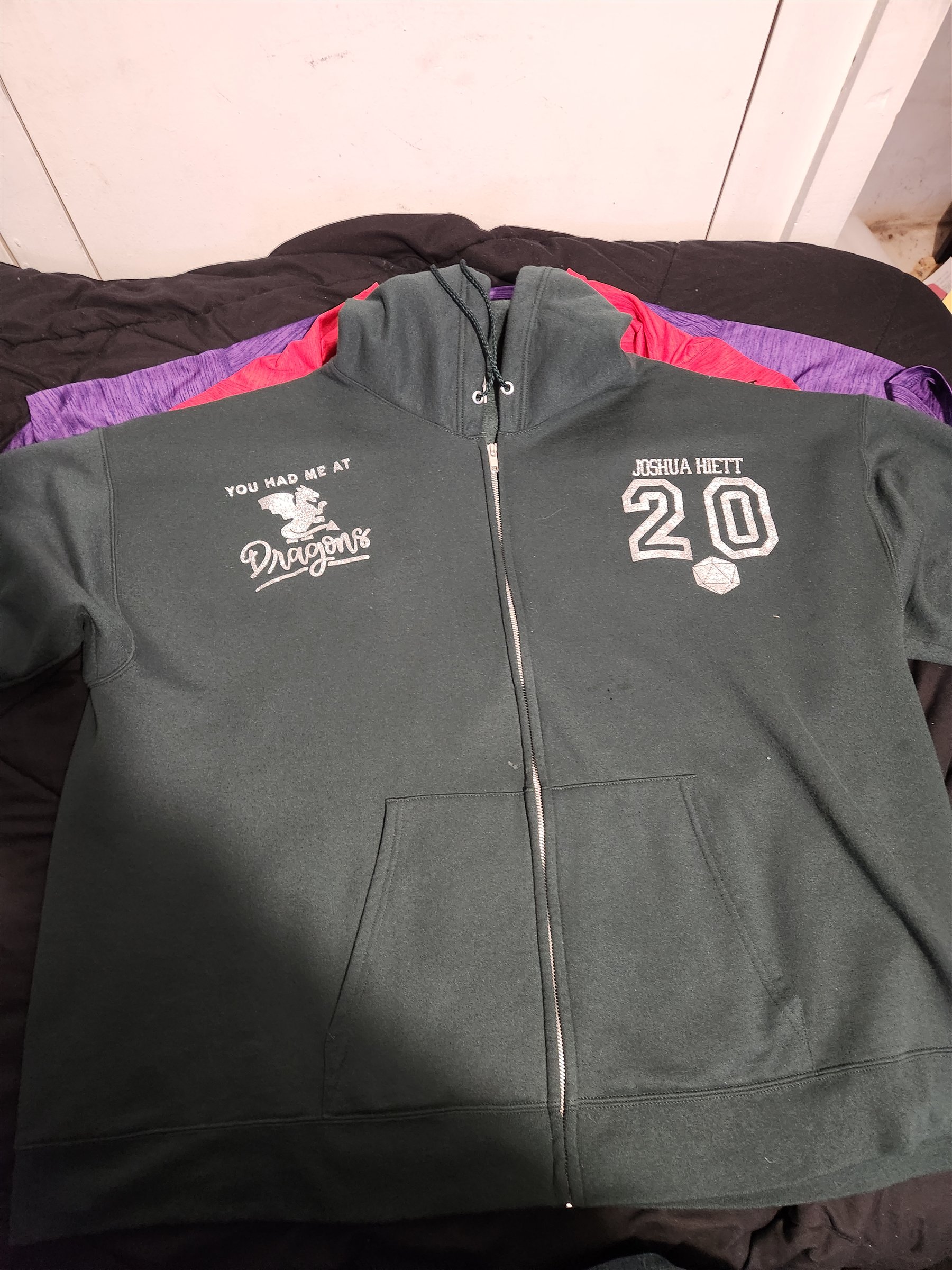 Front of my black zip hoodie with a silver You Had Me at Dragons design, Joshua Hiett name, the number 20, and a twenty-sided die